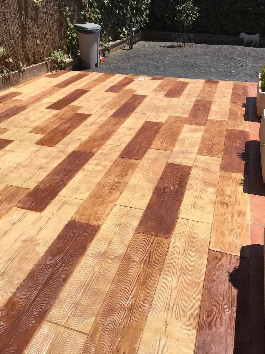 Pavimento de patio con aspecto de madera en baldosas rectangulares alternadas de color marrón claro y oscuro.