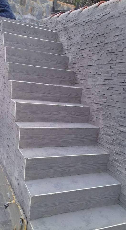 Escalera de piedra gris contra una pared texturizada.