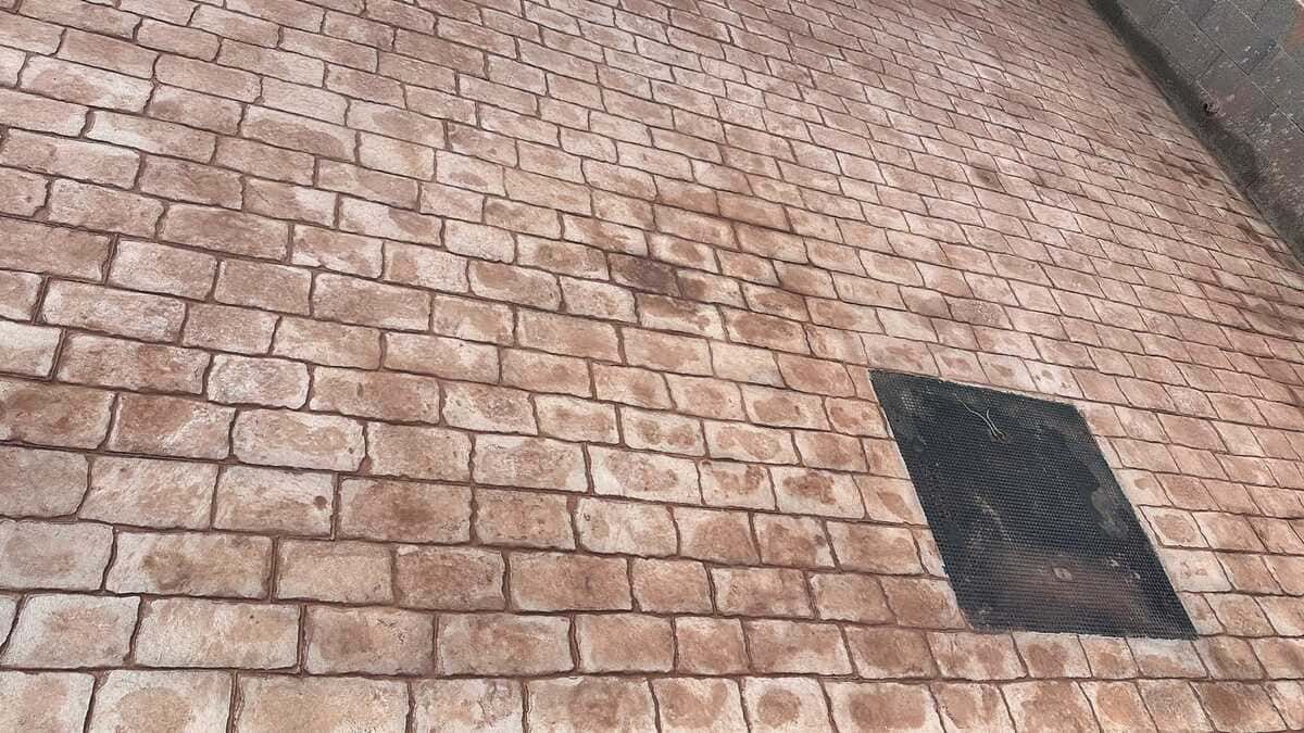 Pared de ladrillo con abertura o respiradero rectangular oscuro.