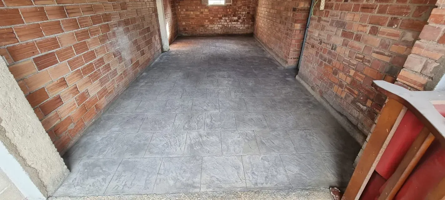 Las paredes de ladrillo enmarcan un piso de concreto gris, con un atisbo de una puerta abierta y una pequeña ventana en la parte posterior.