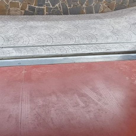 Superficie roja con huellas de neumáticos, borde plateado y pasarela gris estampada.