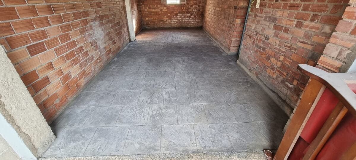 Habitación con paredes de ladrillo y suelo de hormigón. Hay una ventana al fondo. Hay un mueble a la derecha.