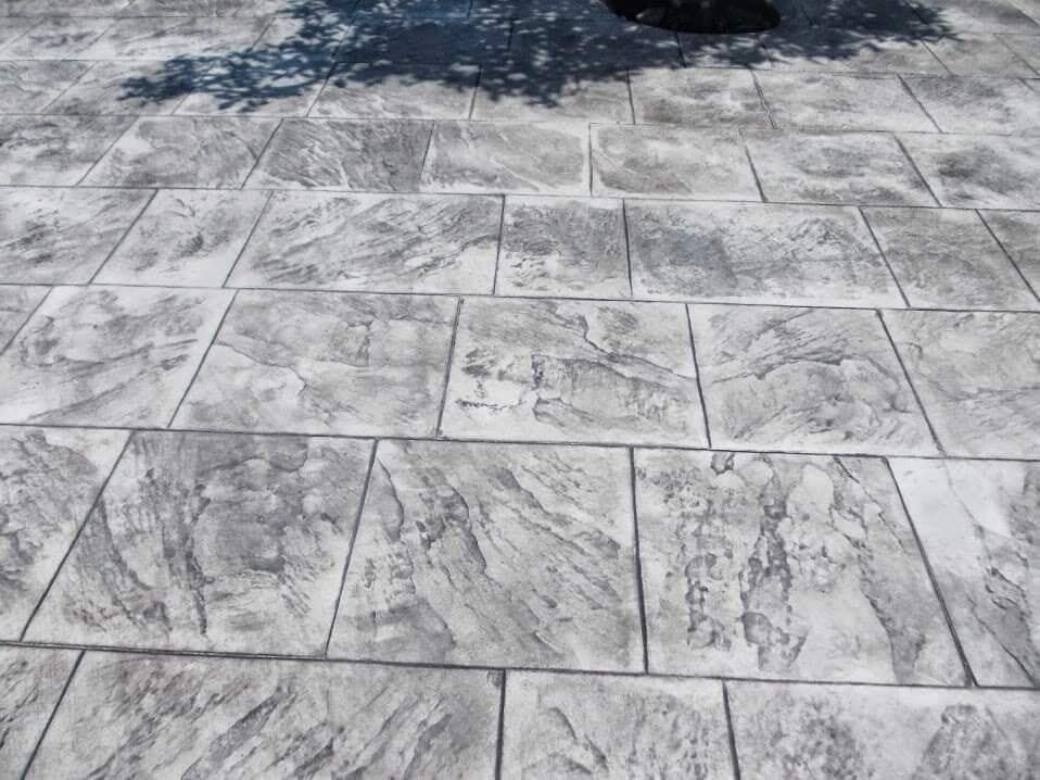 Patio de hormigón estampado con patrón de piedra gris.