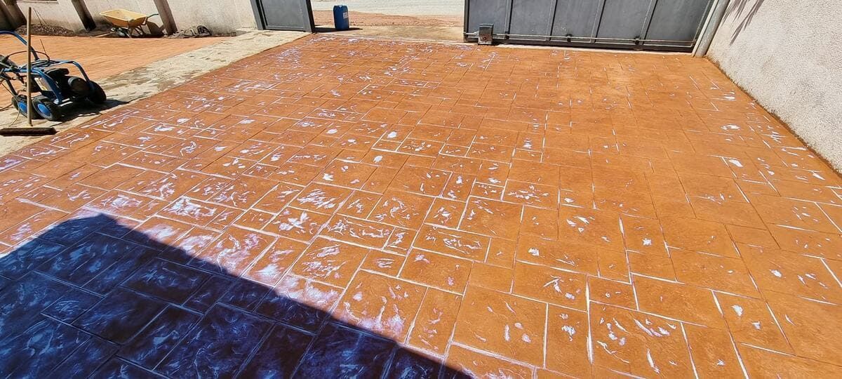 Una superficie pavimentada con ladrillos, de color marrón anaranjado, parece húmeda y espumosa, posiblemente limpiada con agua y jabón.