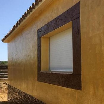 Edificio de estuco amarillo con molduras de ventanas marrones y una ventana cerrada.