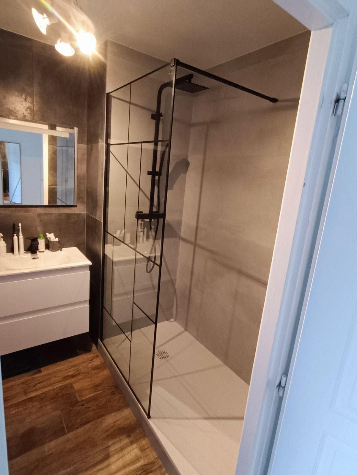 Salle de bains moderne avec une douche à l'italienne en verre, un meuble de lavabo, un miroir et du parquet.