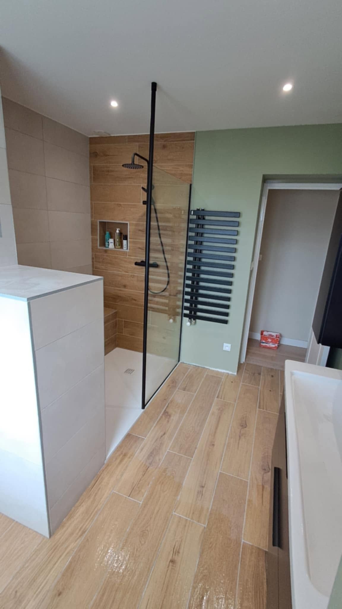 Salle de bains moderne avec du parquet clair, une douche carrelée, de la robinetterie blanche et un mur d'accent vert pâle.