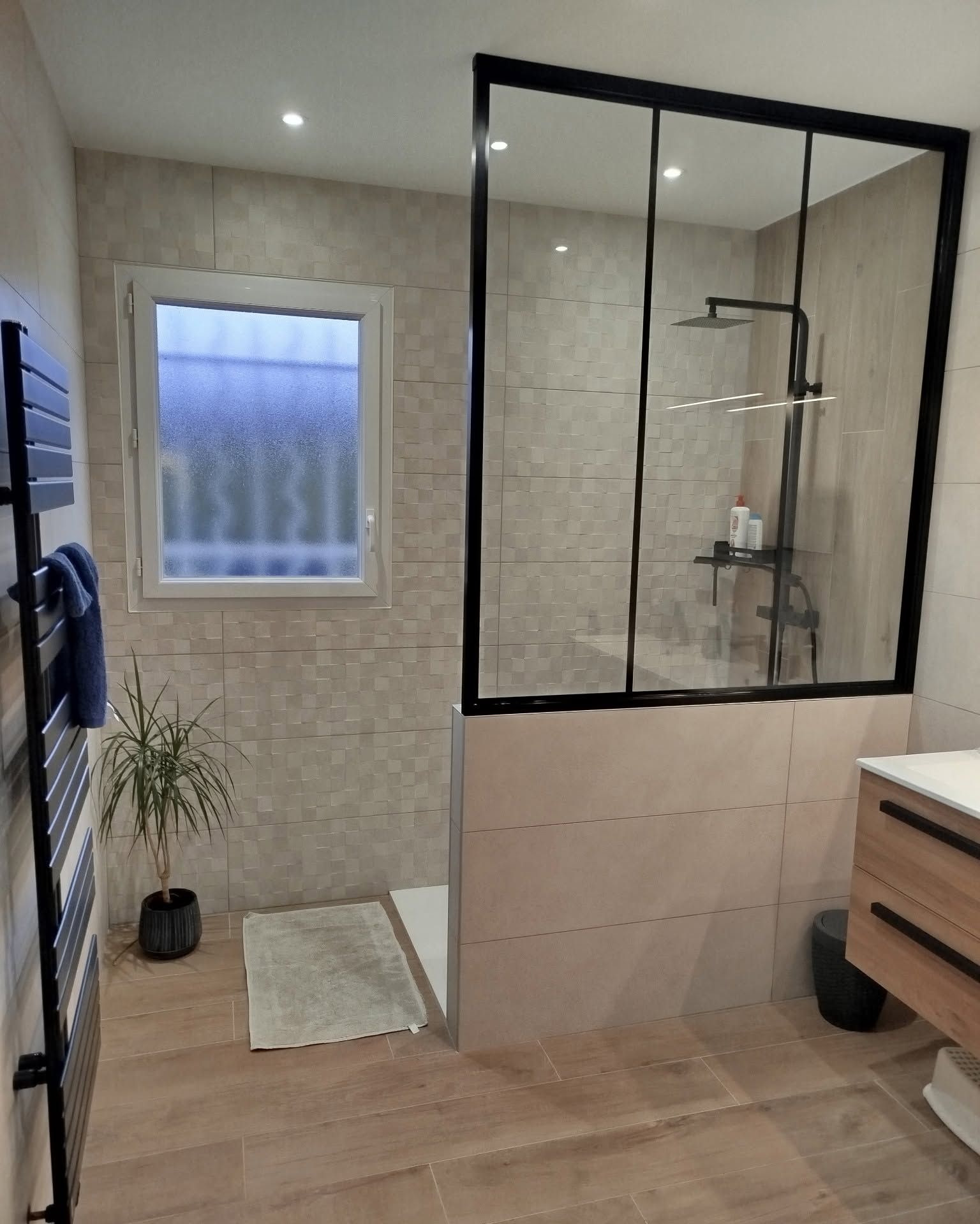 Salle de bains moderne avec une cabine de douche carrelée, une fenêtre, un meuble de lavabo en bois et un parquet clair