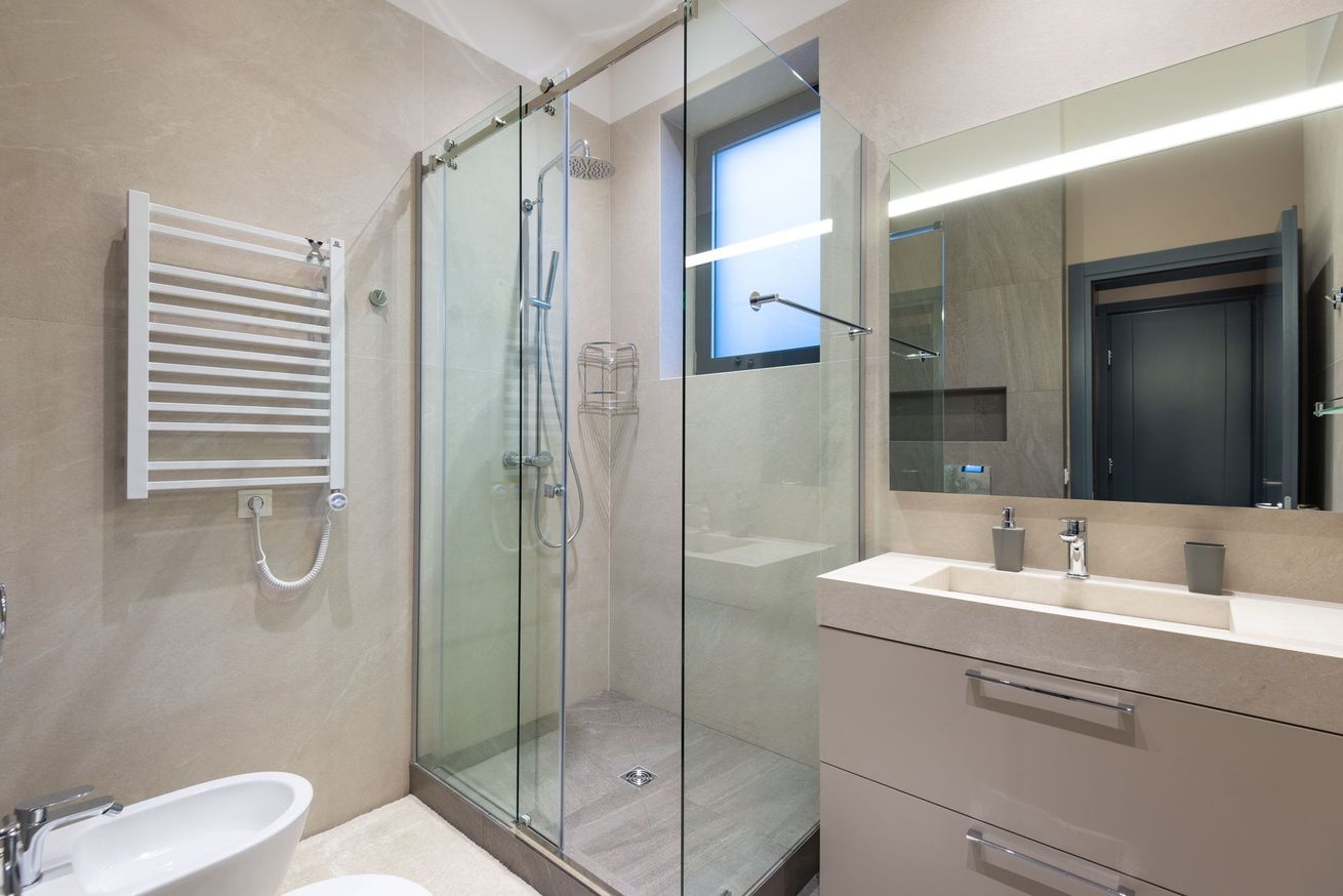 Salle de bains moderne avec une douche en verre, un sèche-serviettes, un meuble vasque et un grand miroir