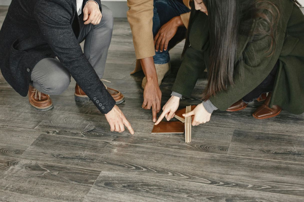 Plusieurs personnes sont accroupies sur un sol, mesurant et et regardant le plancher.
