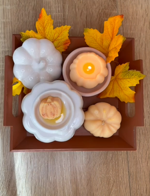 Décoration sur le thème de l'automne : citrouilles, bougies et feuilles jaunes disposées sur un plateau brun.