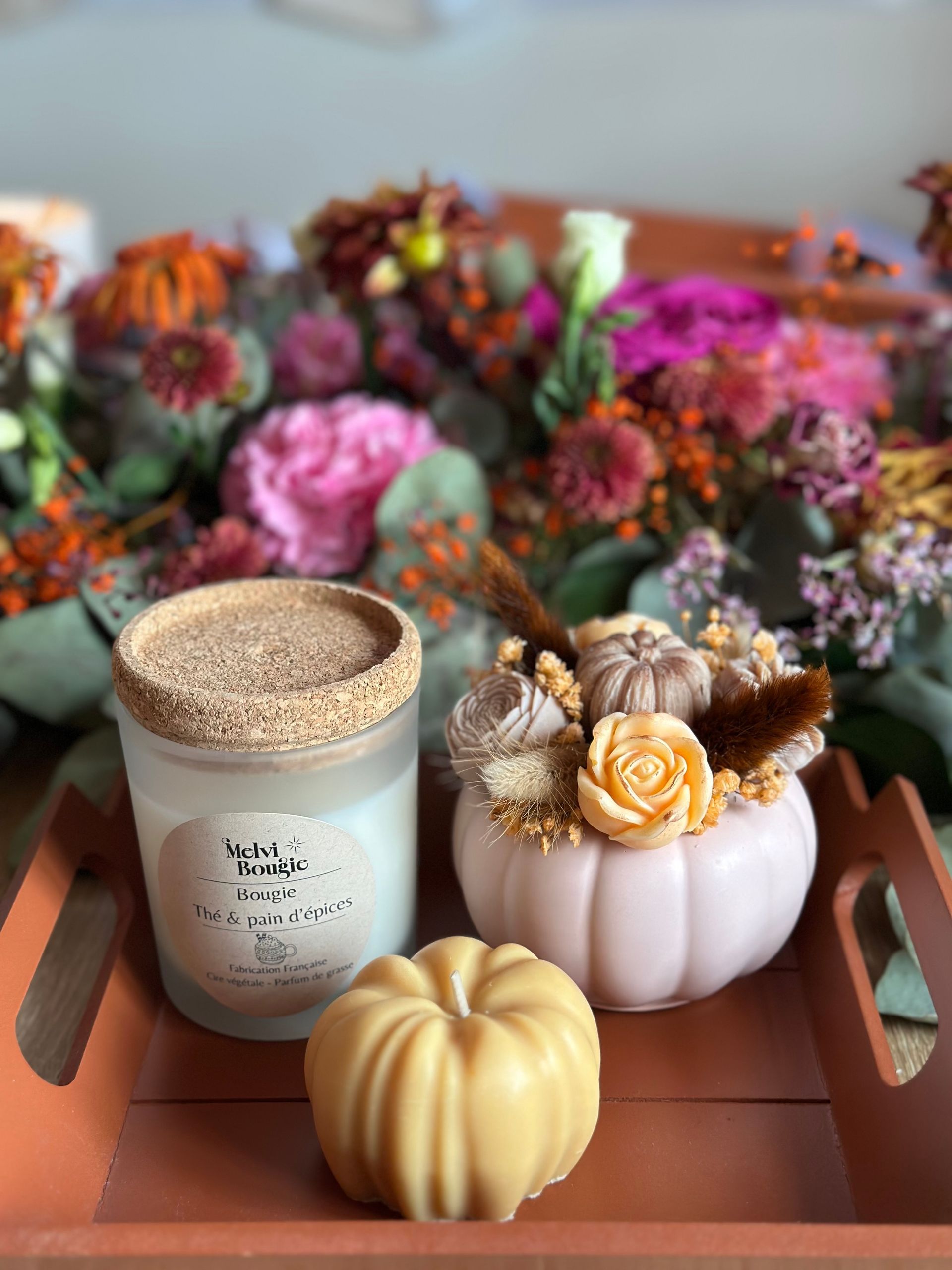 Composition sur le thème de l'automne : bougie, savon en forme de citrouille et centre de table floral sur un plateau.
