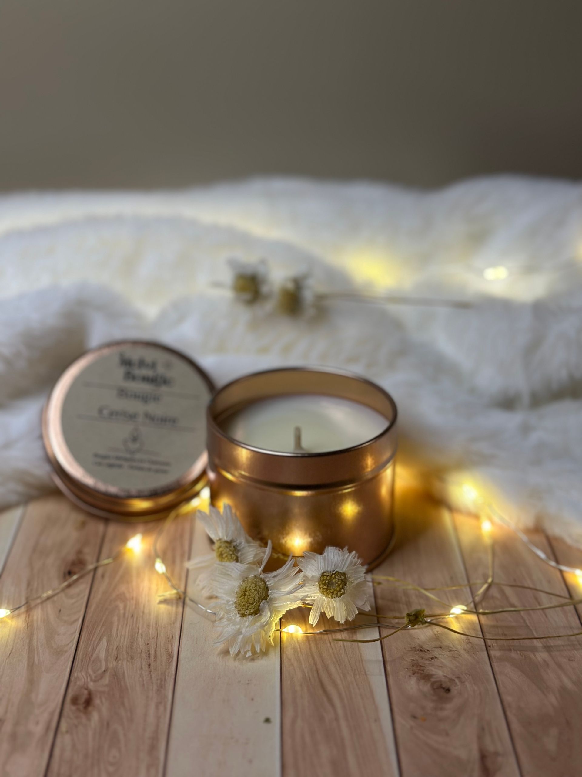 Sapin de Noël en céramique illuminé et bougies sur une surface blanche et moelleuse.