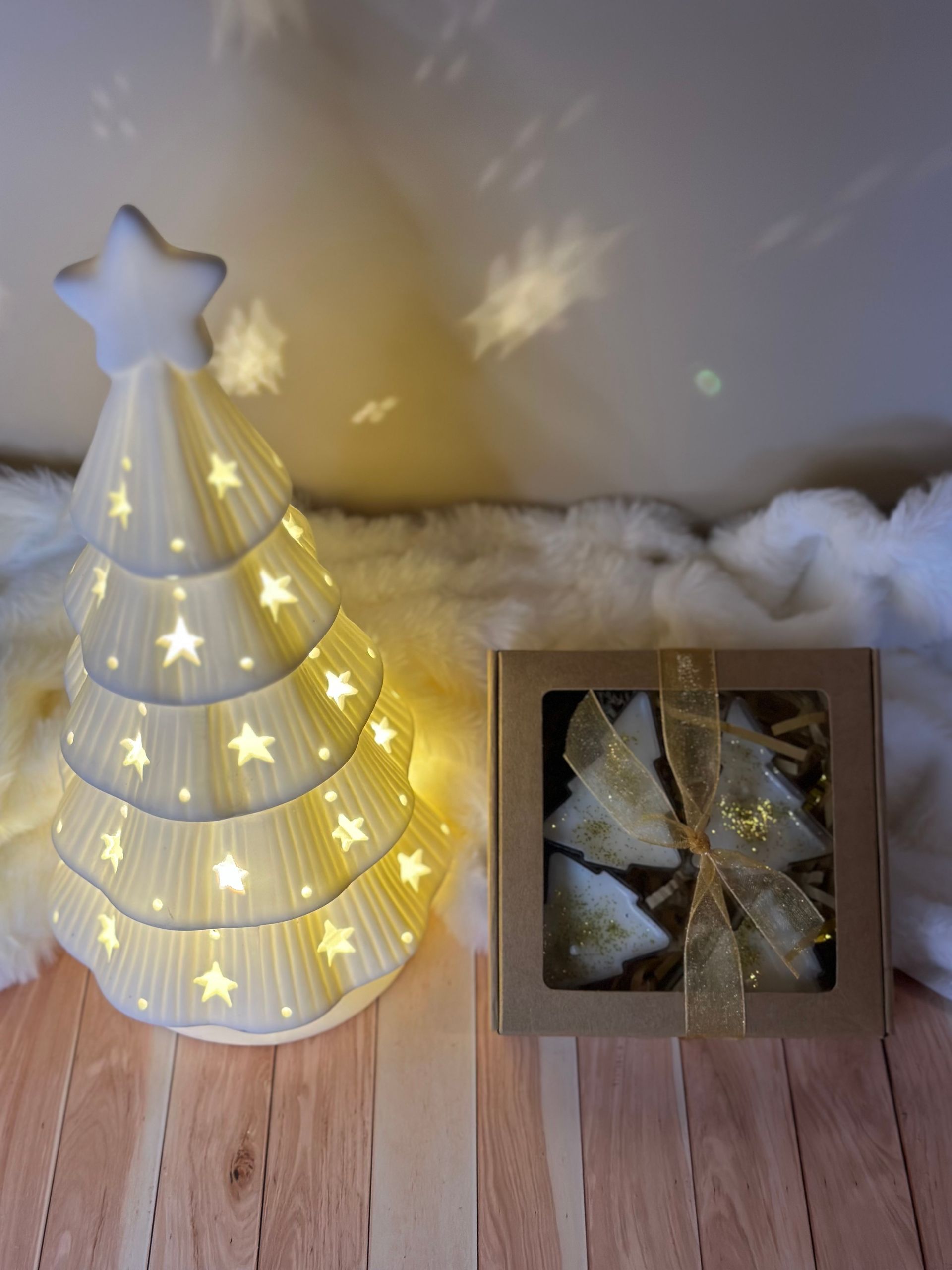 Sapin de Noël en céramique illuminé avec étoile à son sommet, boîte de biscuits en forme de sapin sur support en bois.