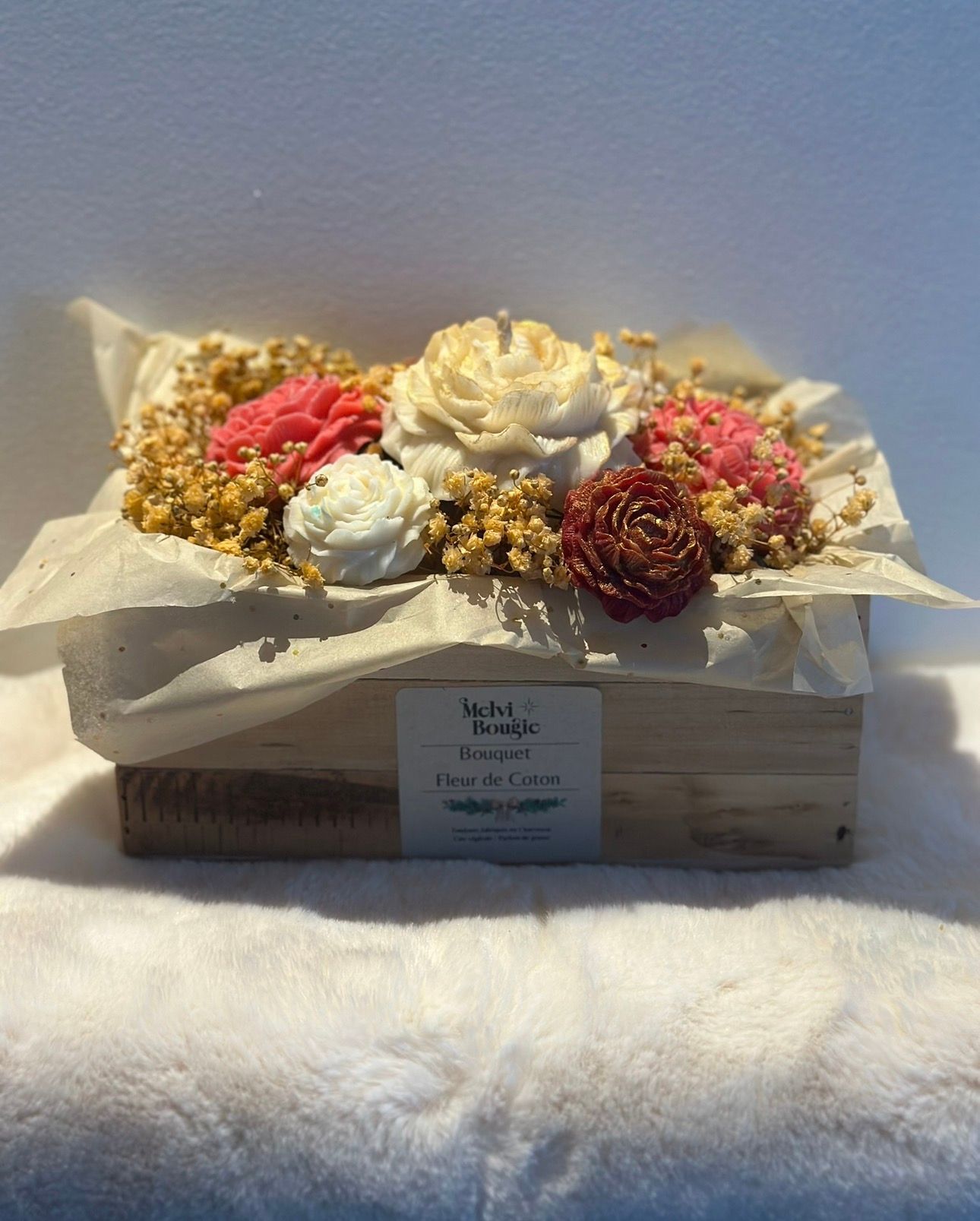 Décorations de Noël sur une surface en fausse fourrure blanche : traîneau, sapin en spirale, globe transparent avec scène miniature.