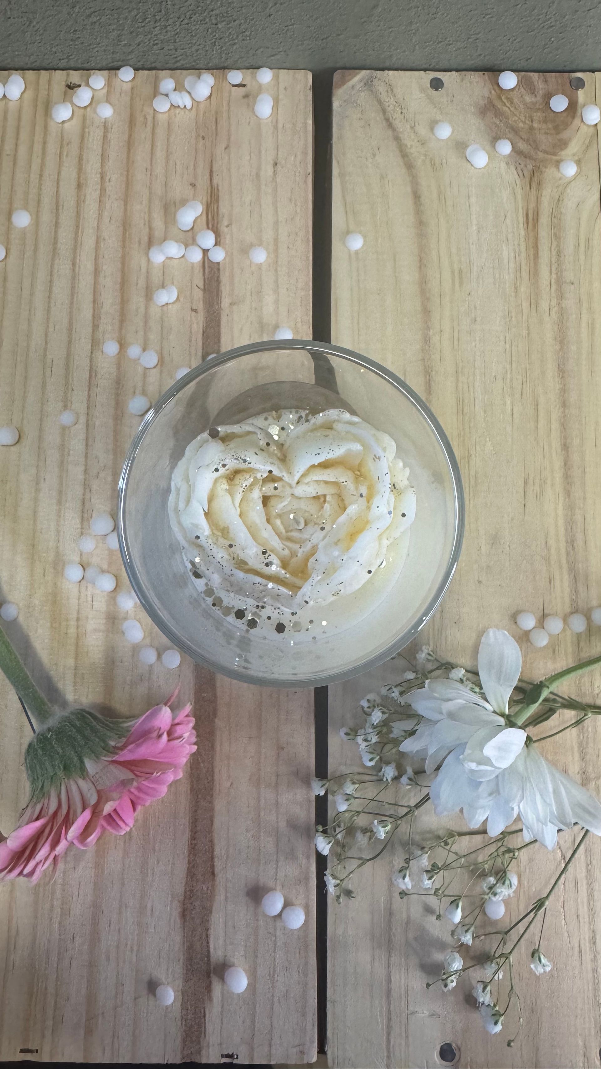 Main tenant un compte-gouttes versant du liquide dans un flacon ; flacons posés sur une surface blanche.