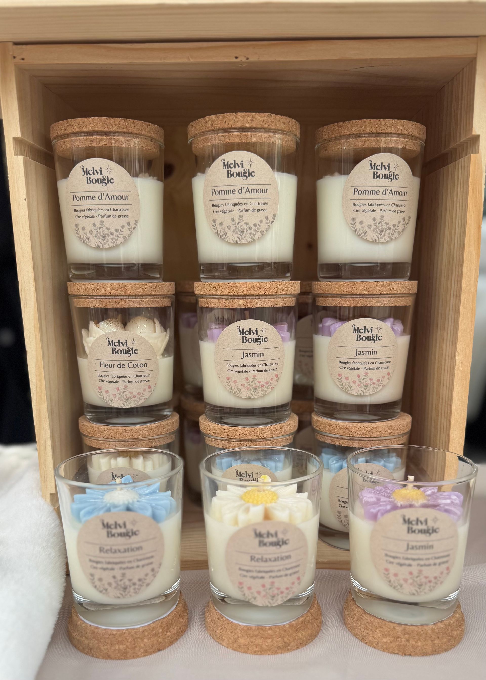 Bougie dans un verre, décorée d'une citrouille, avec des fleurs en arrière-plan.