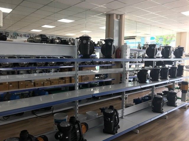 Un interior de tienda bien iluminado con filas de estantes que muestran bombas de agua y equipos.
