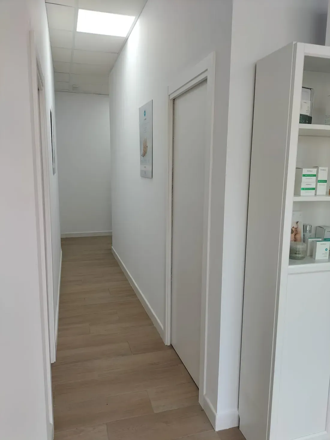Un largo pasillo con pisos de madera y paredes blancas en una habitación.