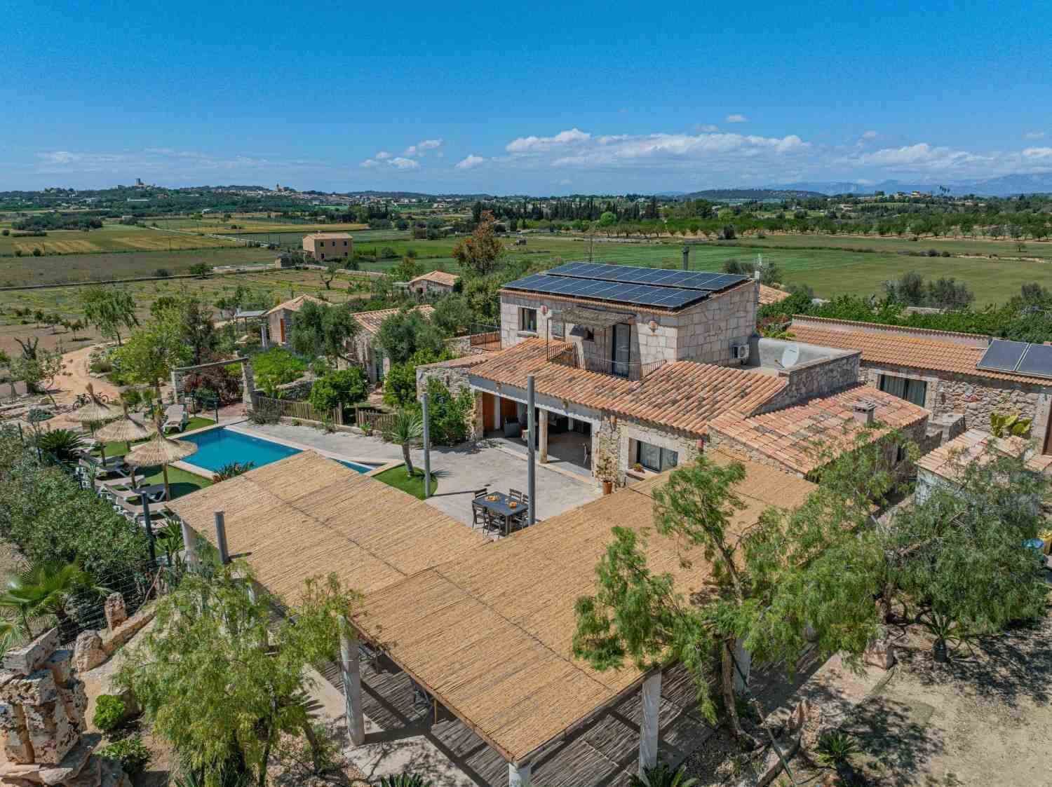 Villa moderna con techo de terracota, piscina y exuberantes jardines con vistas al campo abierto.