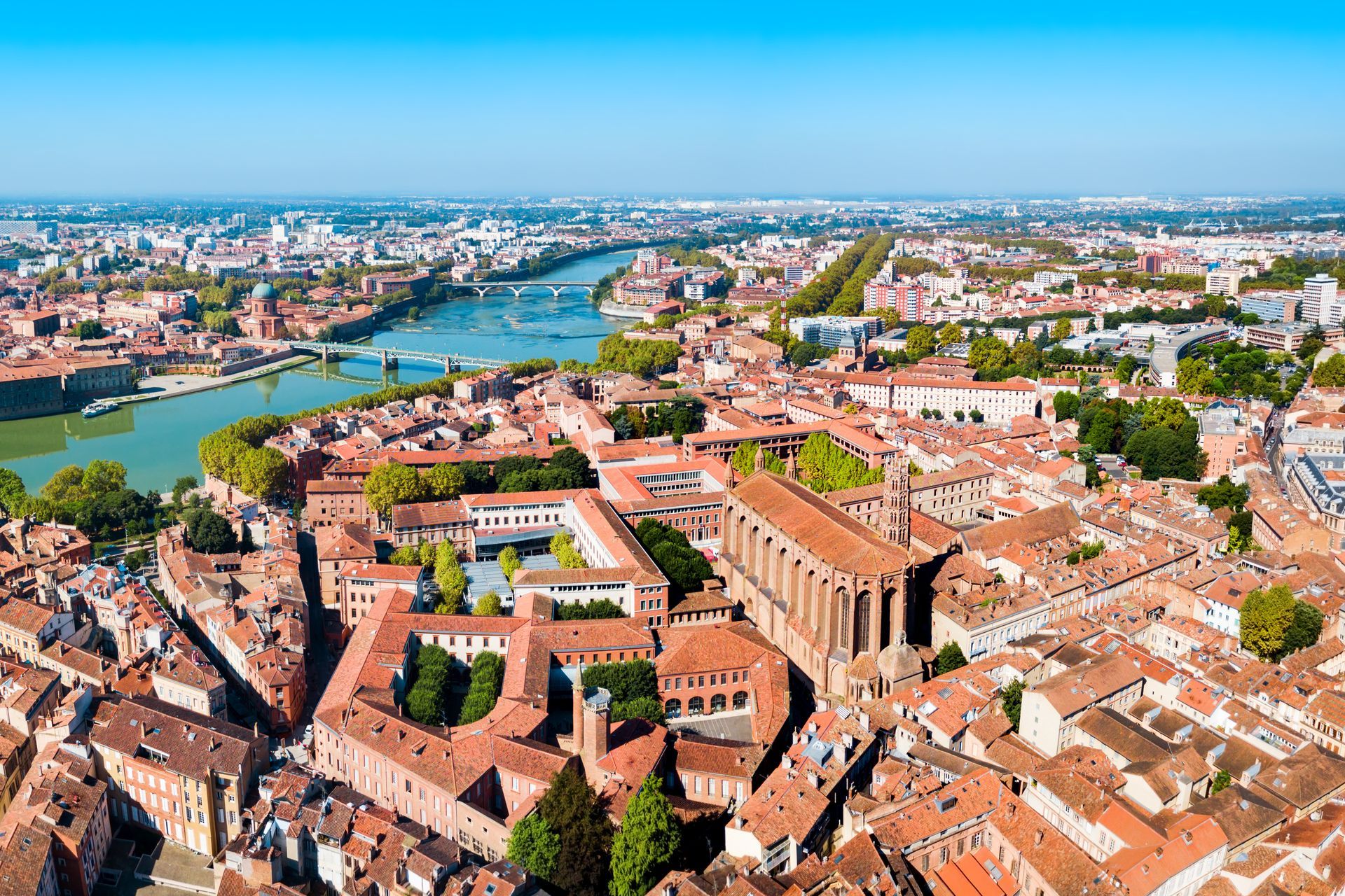 Vue aérienne de Toulouse, France, avec des toits de tuiles rouges, la Garonne et le ciel bleu.