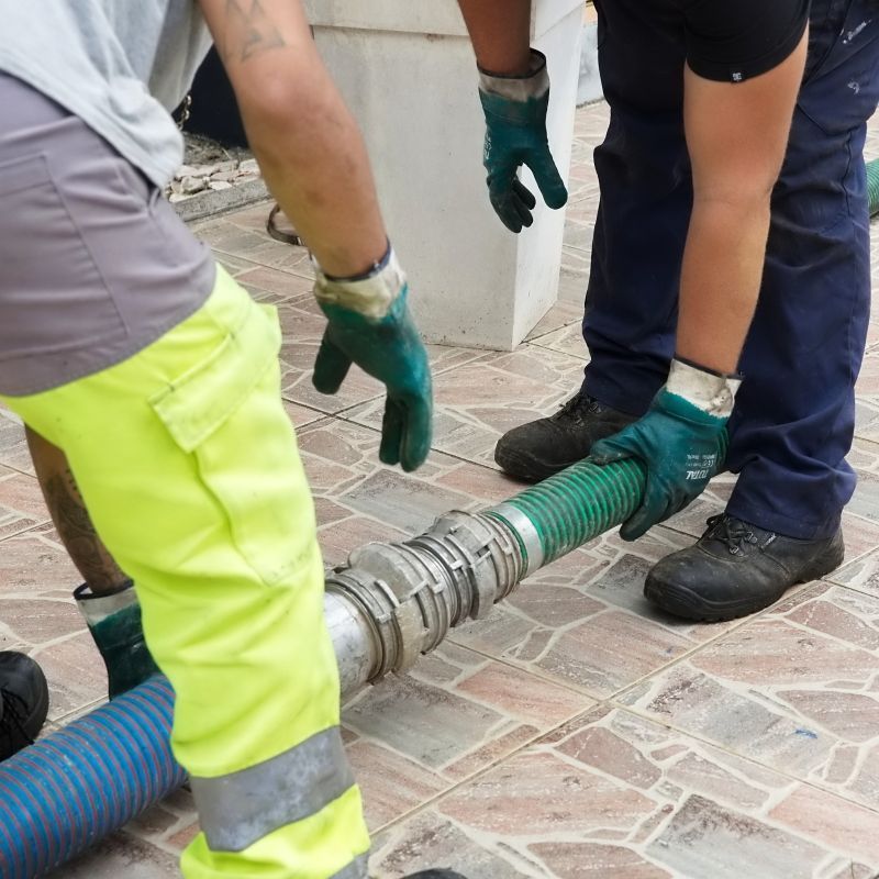 Deux professionnels à proximité d'un tuyau de vidange.