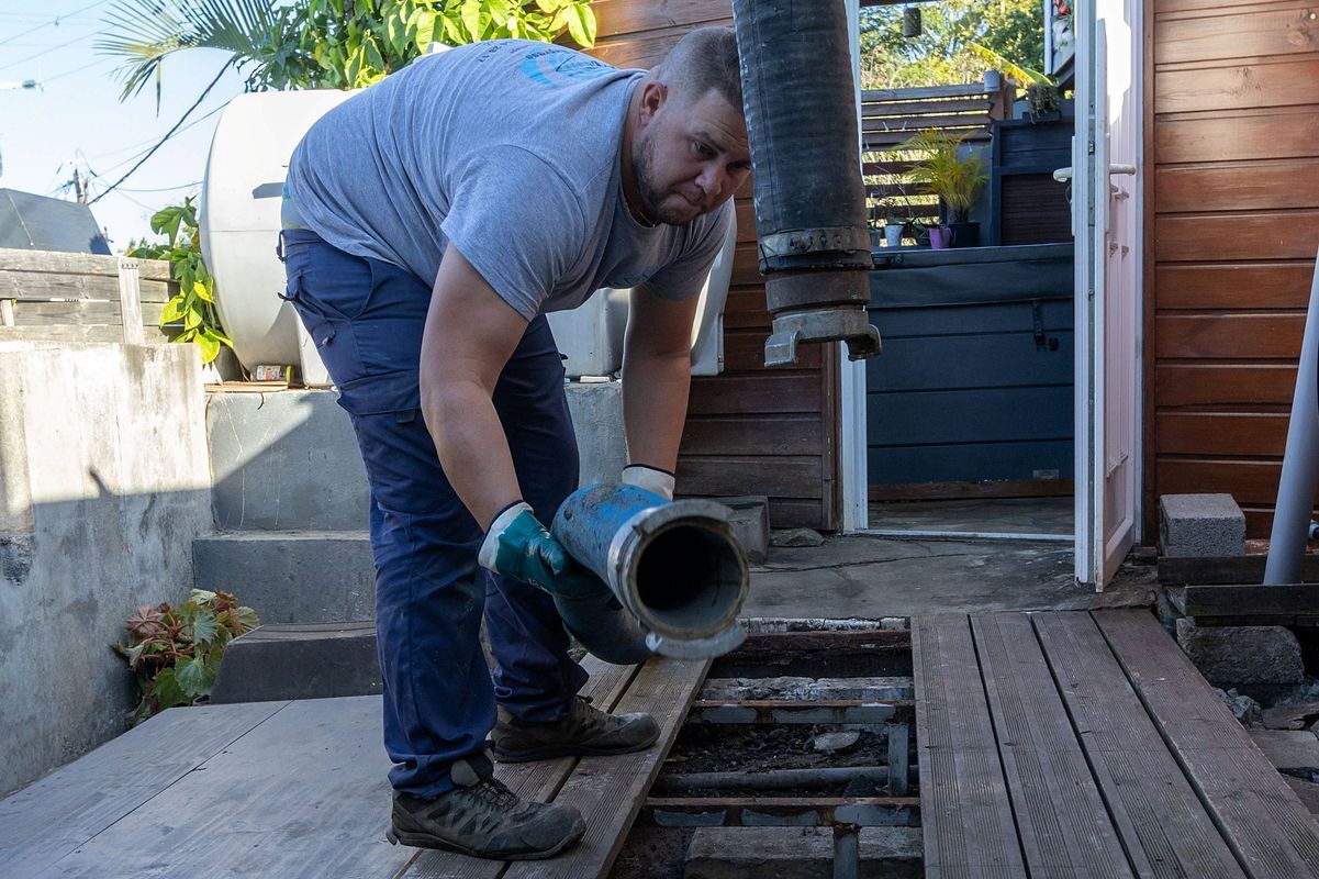Professionnel reliant deux tuyaux sur une terrasse.