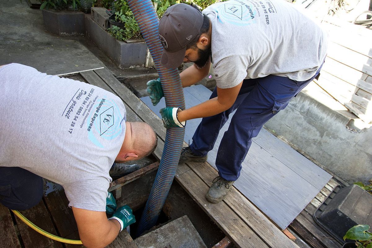Deux professionnels s'entraidant pour manipuler un tuyau lors d'une vidange.