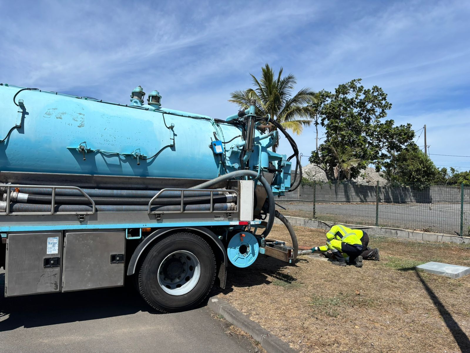 Professionnel penché près d'une bouche d'égout à l'arrière d'un camion de vidange.