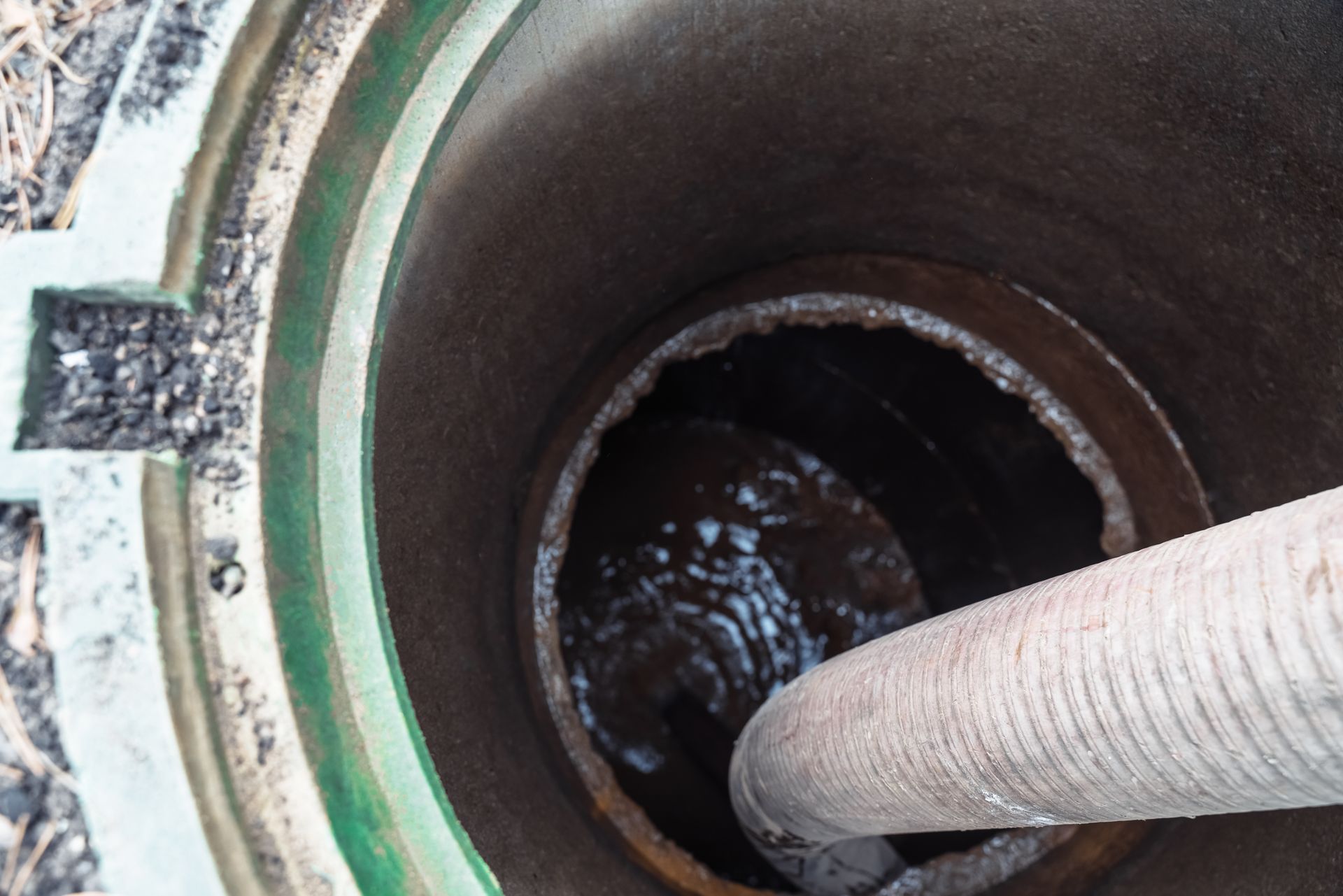 Gros plan sur un tuyau rentrant dans une bouche d'égout.