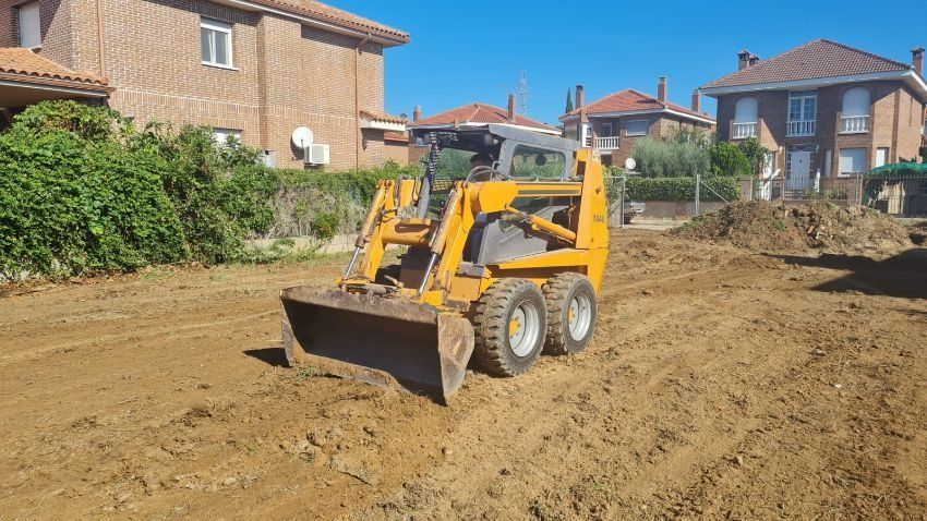 Una excavadora amarilla avanza por un campo de tierra