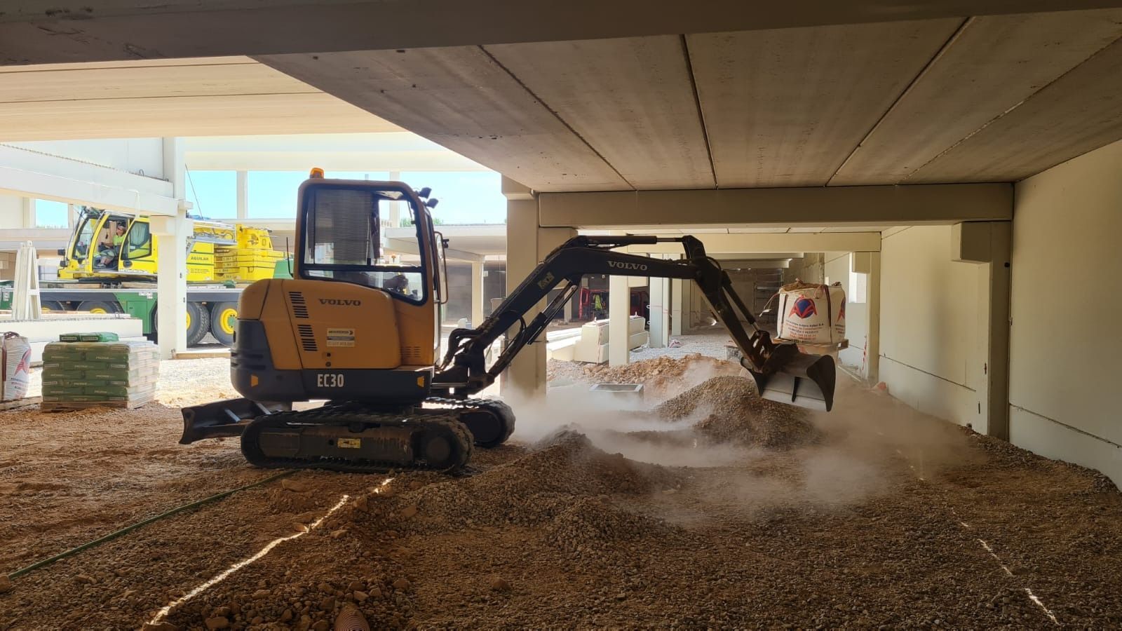 Una pequeña excavadora está moviendo tierra en un edificio en construcción.
