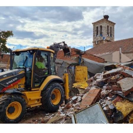 Un tractor Volvo amarillo está trabajando en una pila de escombros.