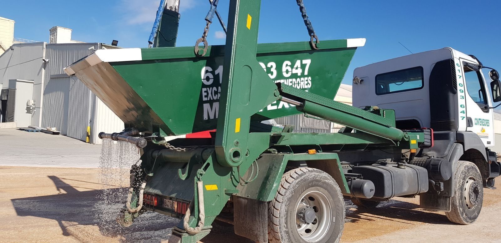 Se está cargando un contenedor verde en un camión.