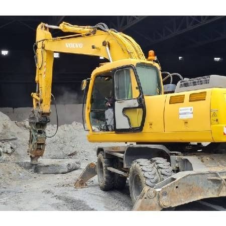 Una excavadora Volvo amarilla está estacionada en un almacén.