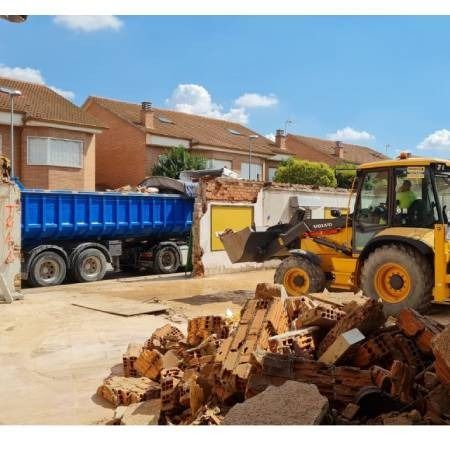 Una excavadora está cargando madera en un camión volquete.