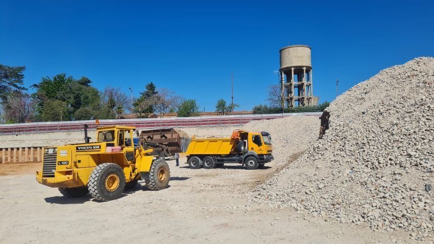 Un camión volquete y una excavadora están estacionados al lado de una pila de grava.