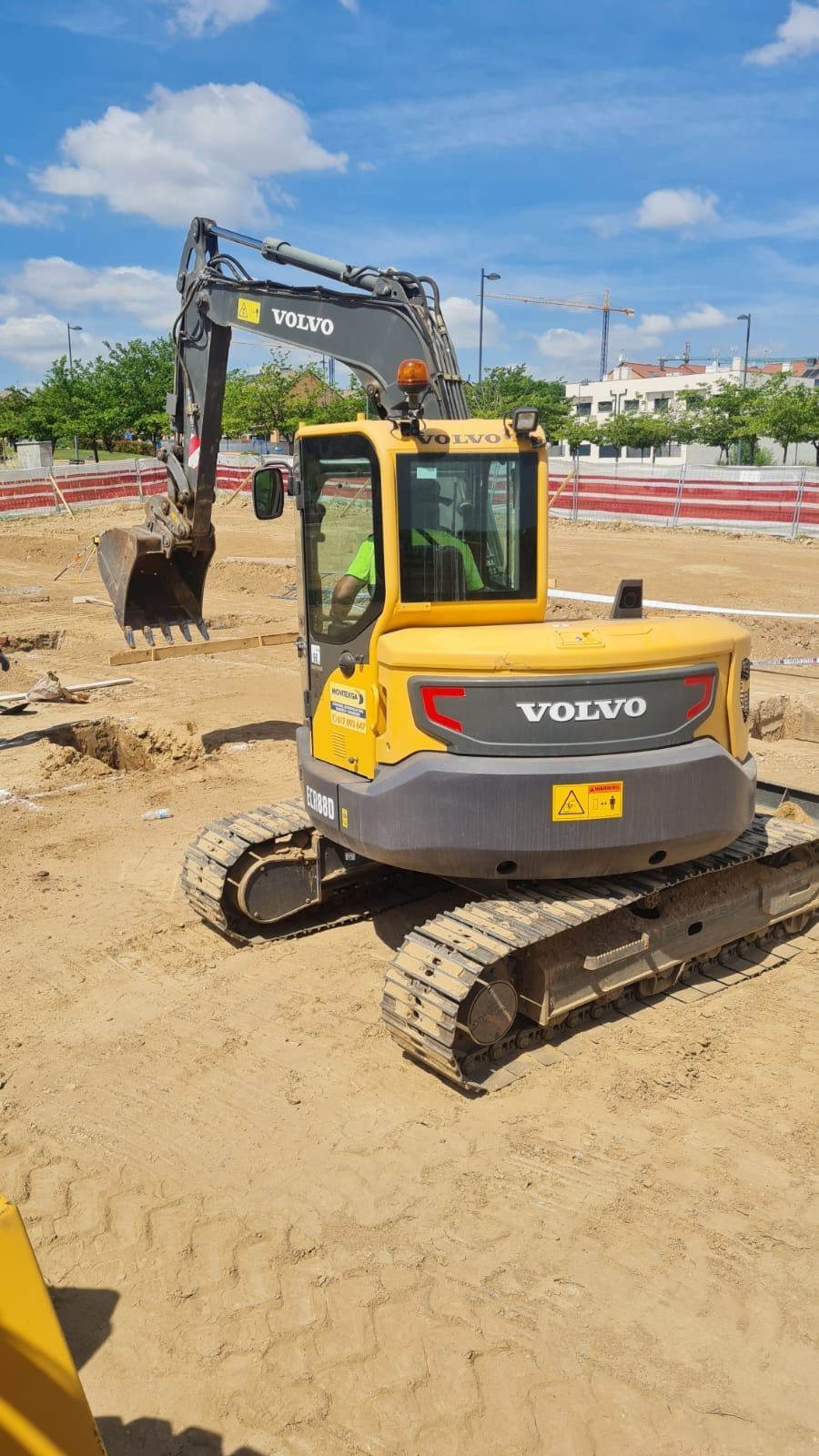 Una excavadora amarilla y gris está estacionada en un campo de tierra.