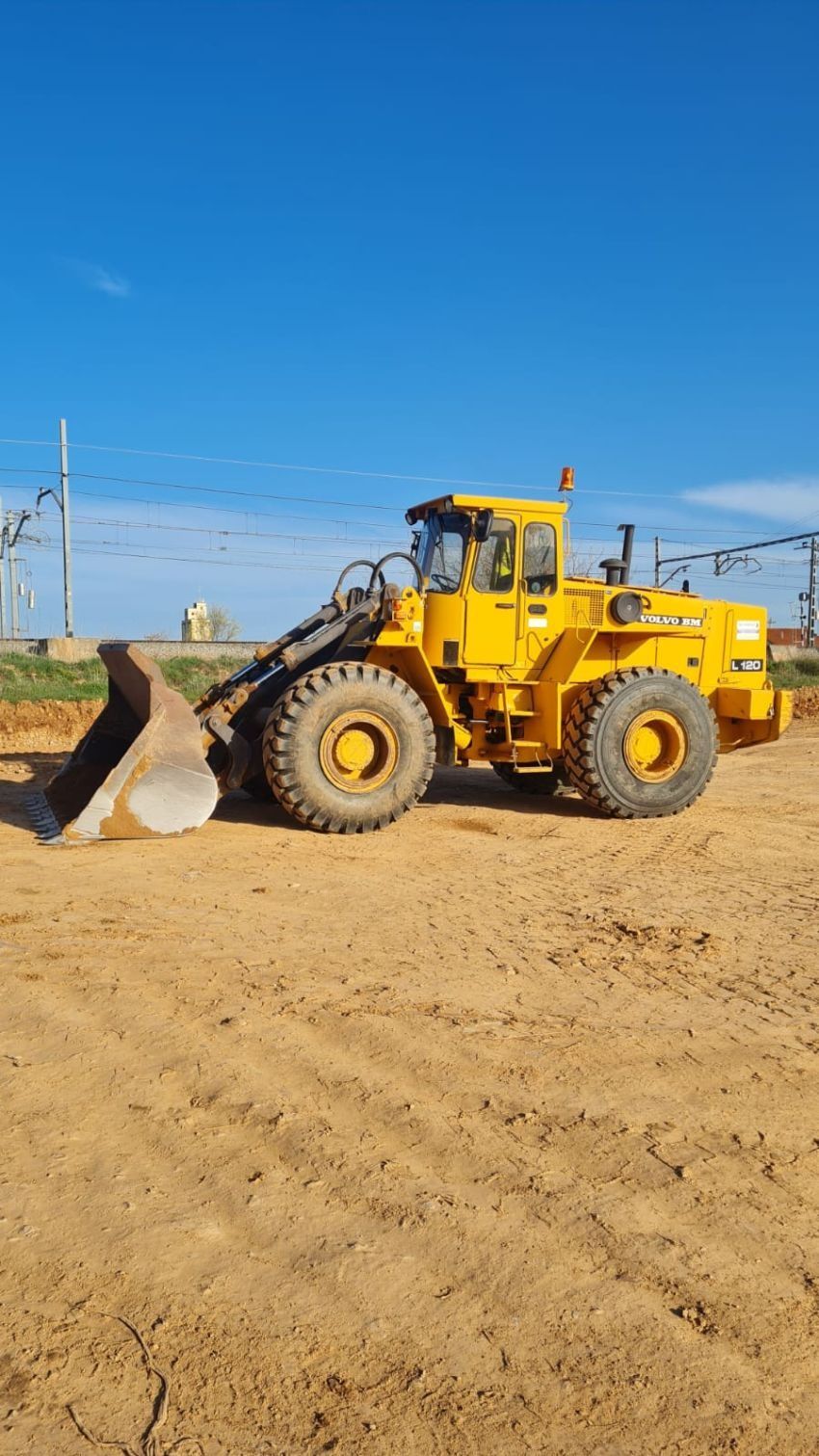 Una excavadora amarilla está estacionada en un campo de tierra.
