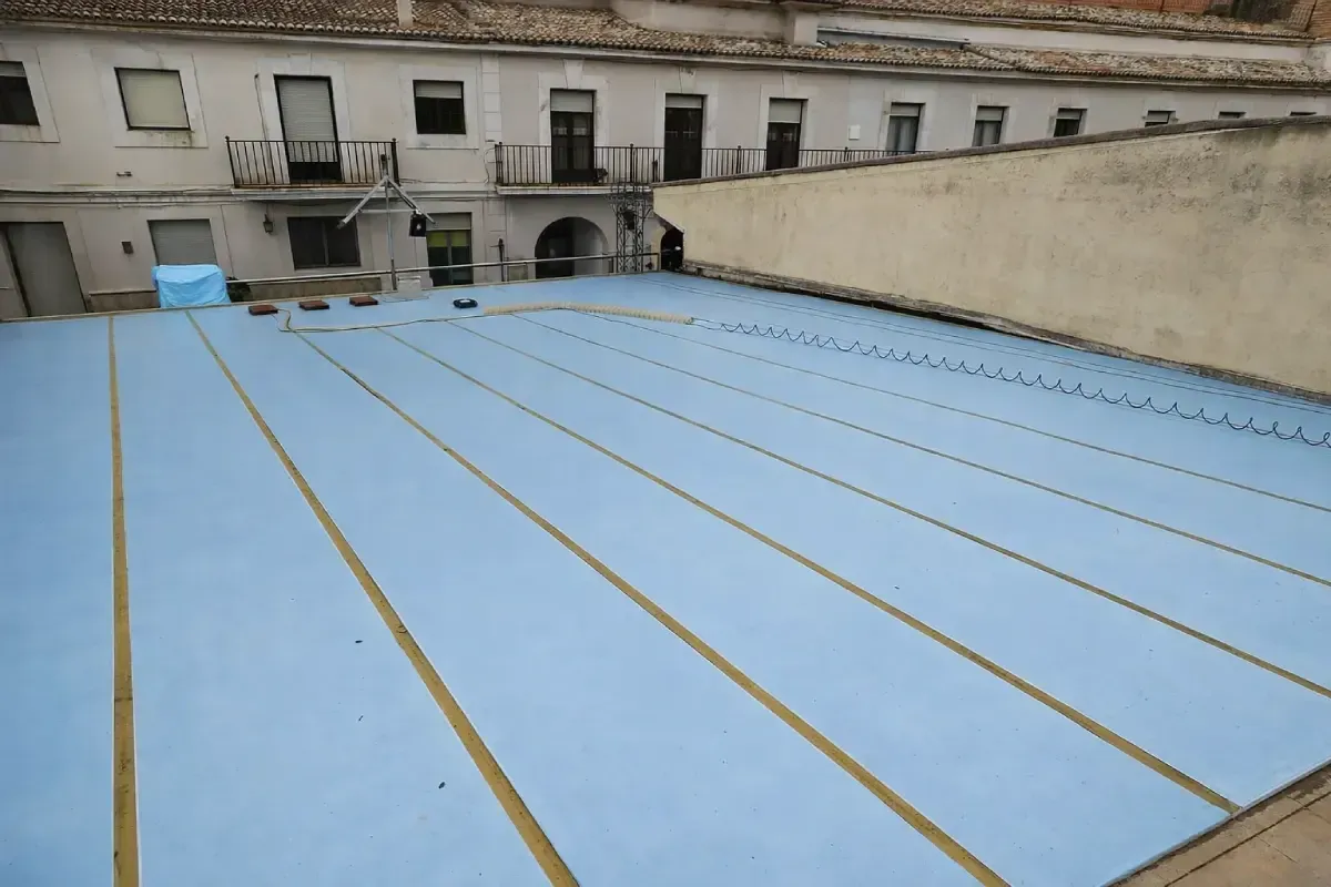 Vista panorámica de una instalación de membrana de techo industrial plana de color azul claro en la terraza de un edificio.