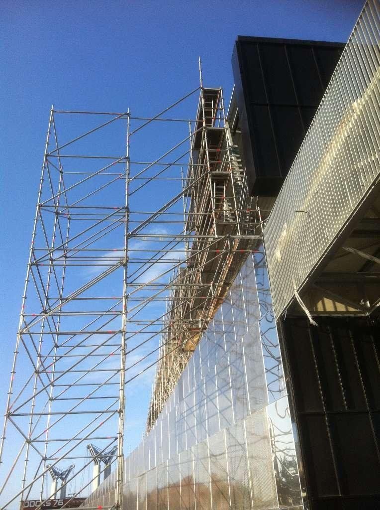 Échafaudage sur un immeuble de grande hauteur, bâche de protection sur le mur.