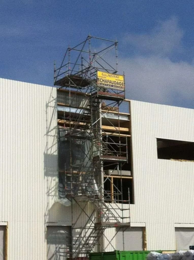 Échafaudage à côté d'un bâtiment, permettant l'accès à une ouverture.