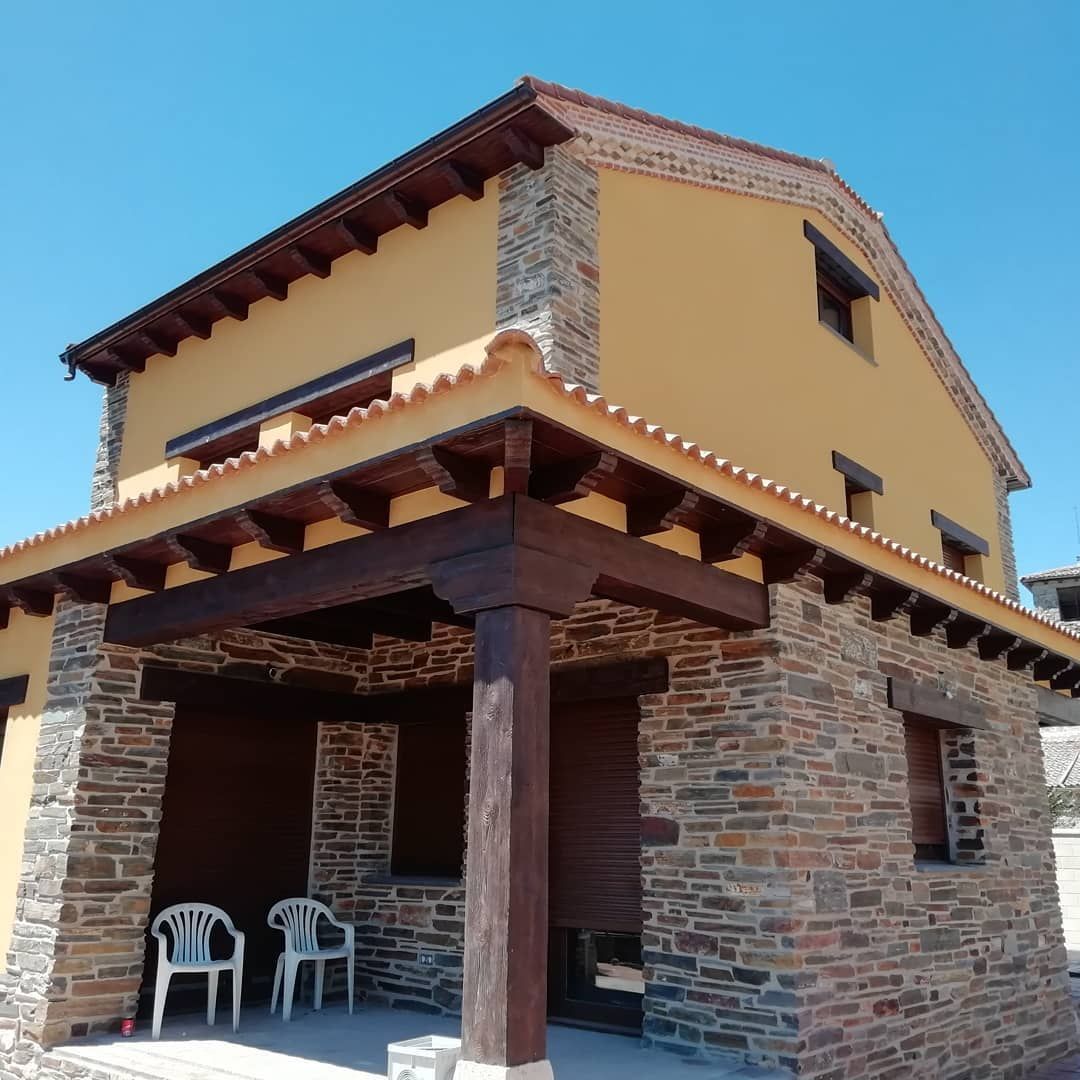 Una casa amarilla con un porche de piedra y sillas