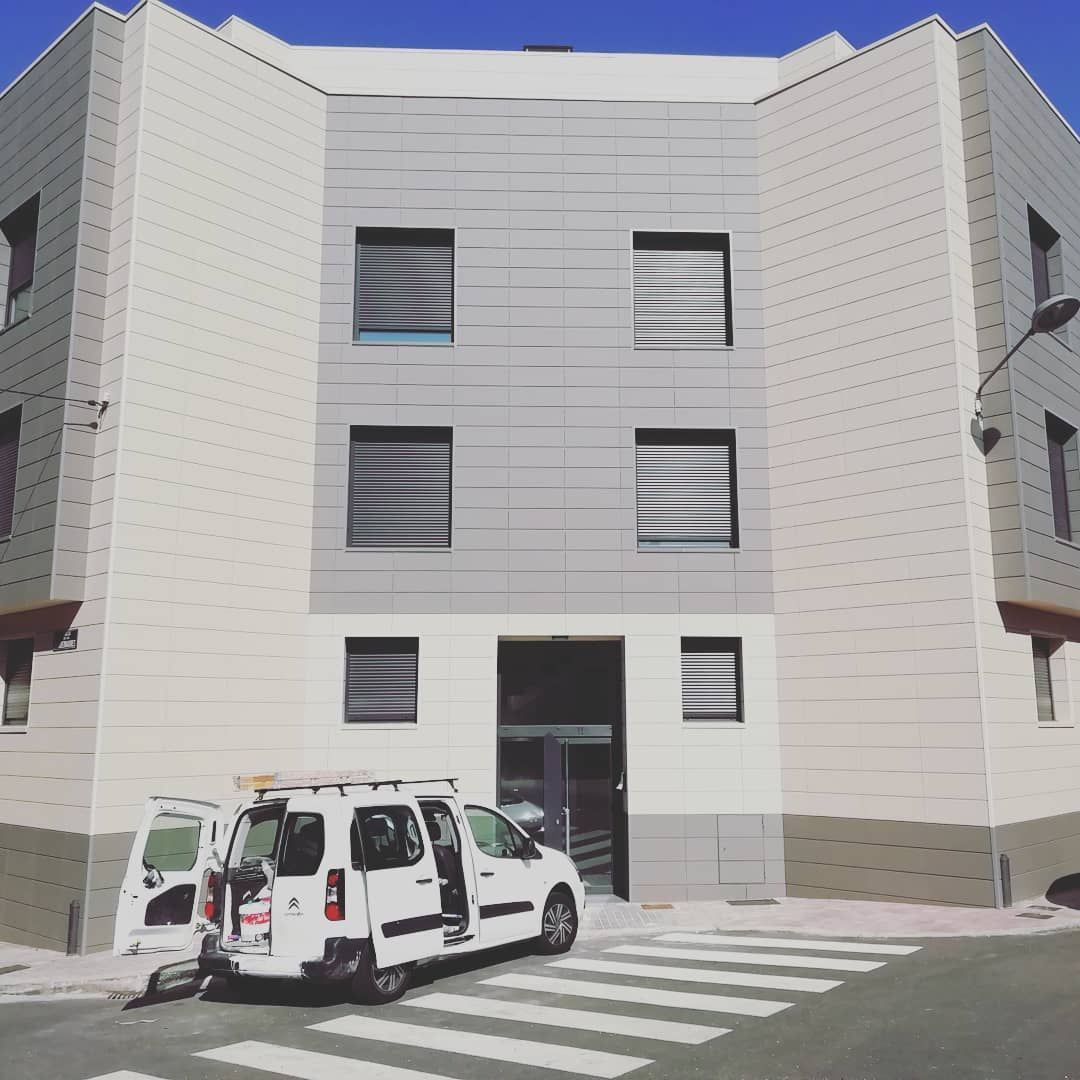 Una camioneta blanca está estacionada frente a un edificio