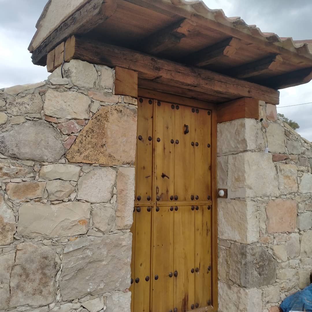 Un muro de piedra con una puerta de madera y un techo.
