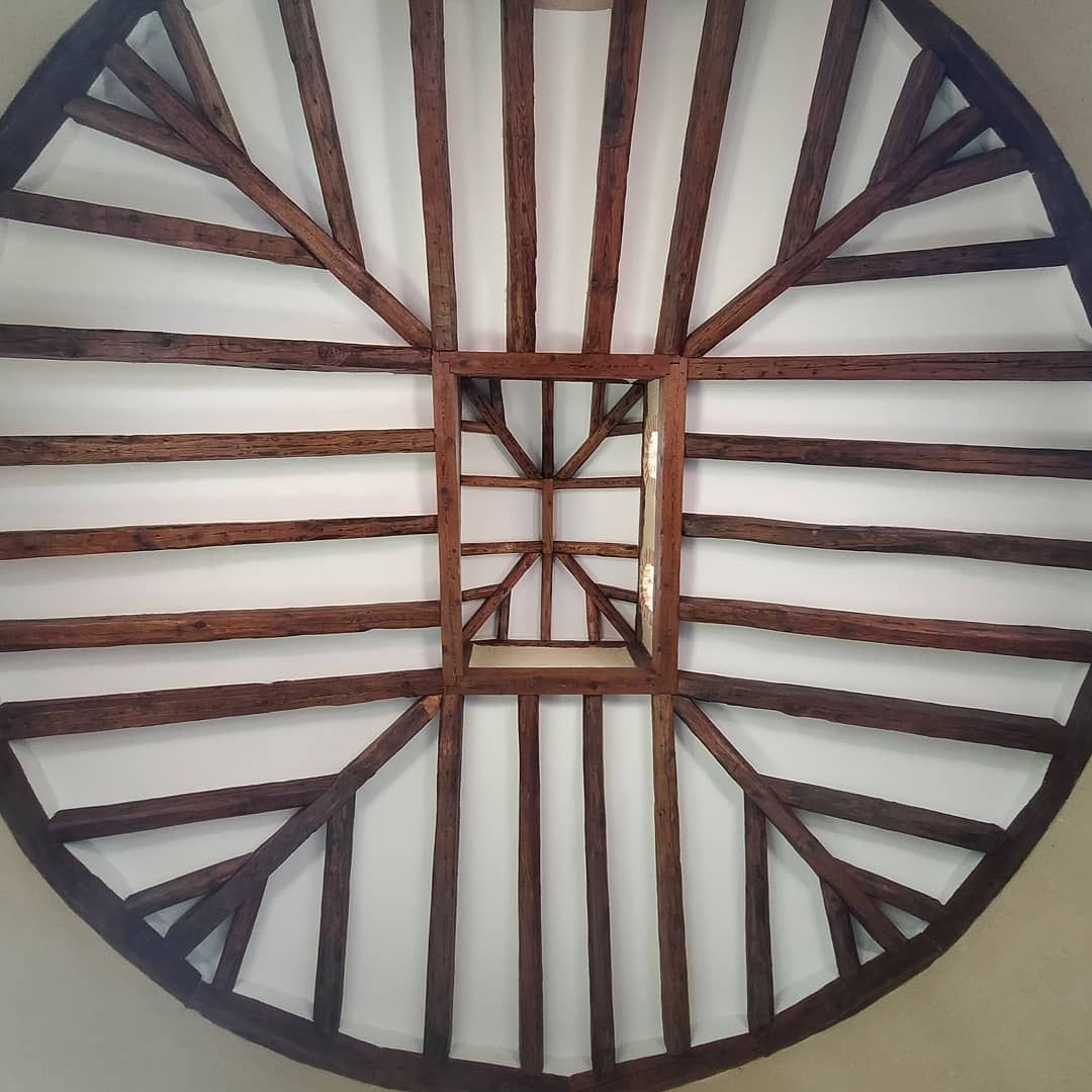 Un techo circular con vigas de madera y un cuadrado en el medio.