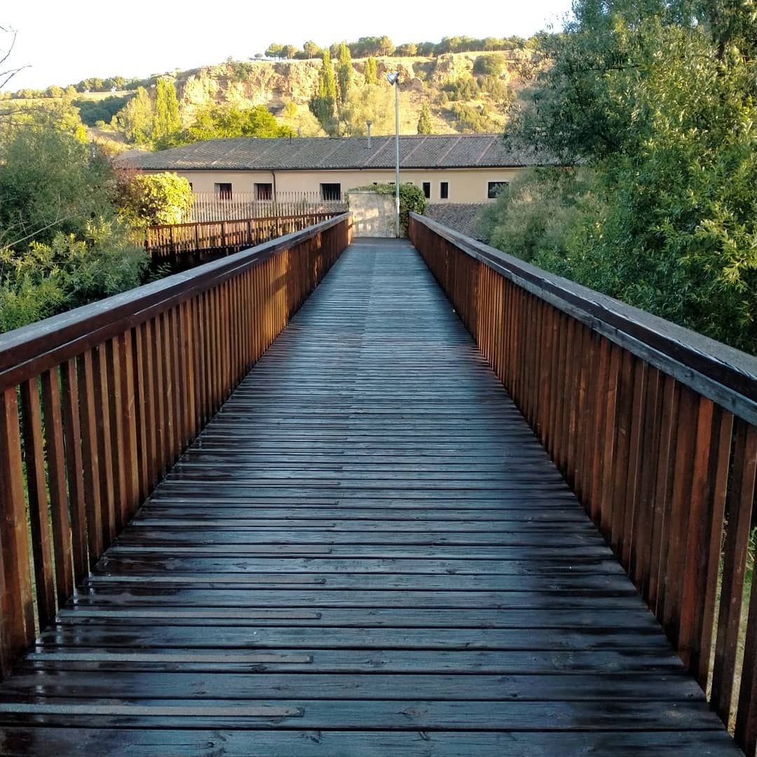 Un puente de madera conduce a un edificio en la distancia.