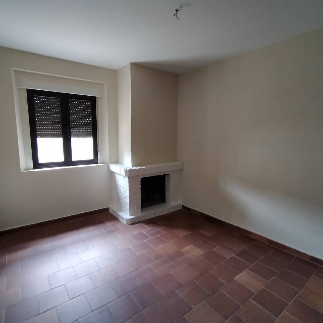 Una habitación vacía con chimenea y una ventana.