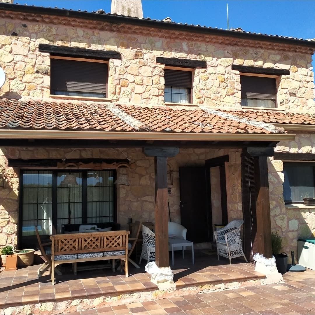 Una gran casa de piedra con porche y sillas.