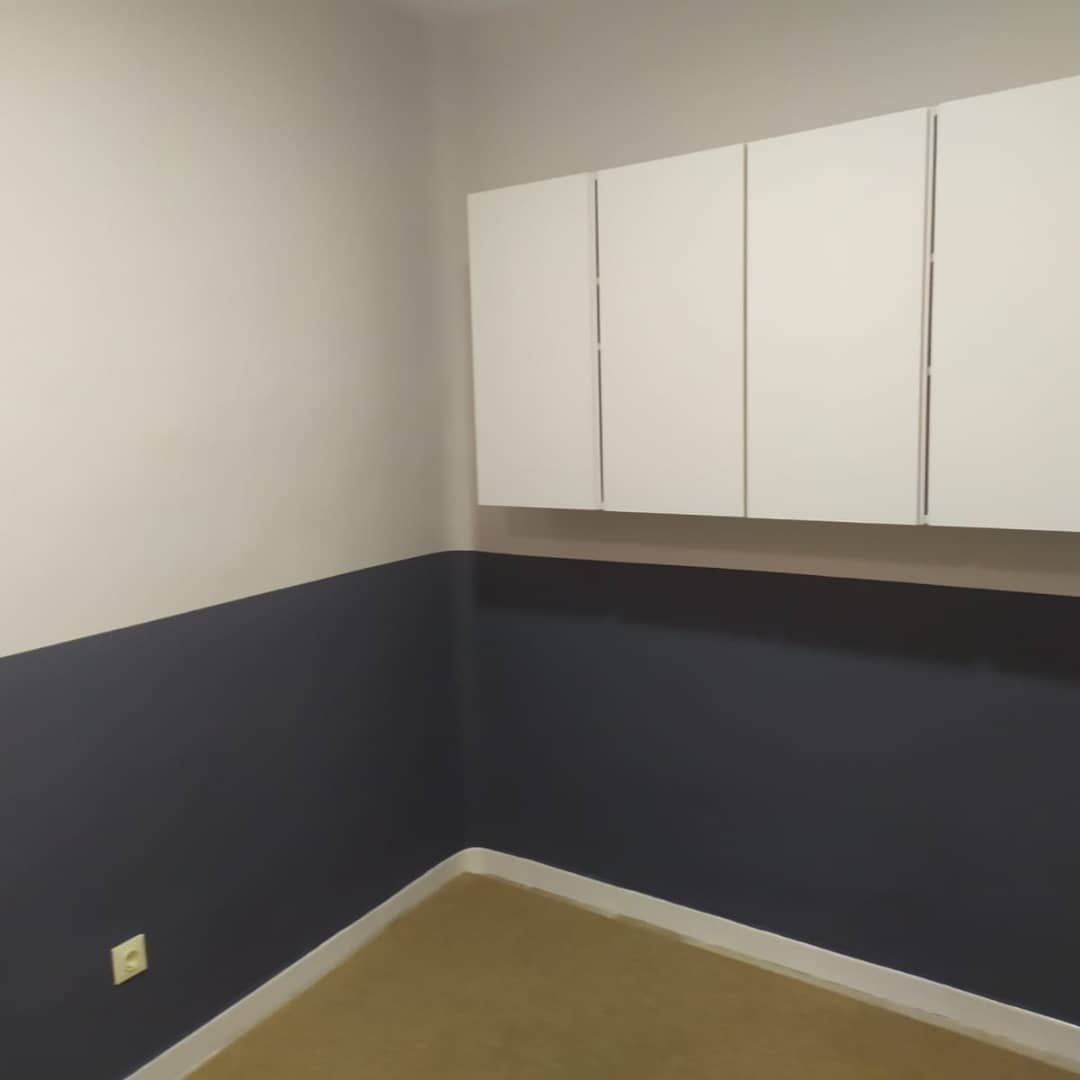 Una habitación vacía con paredes azules y armarios blancos.